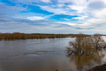 Fototapeta premium early spring flood, high water in the countryside, river overflowing its banks, trees in the water, flooded banks, environmental pollution, ecology