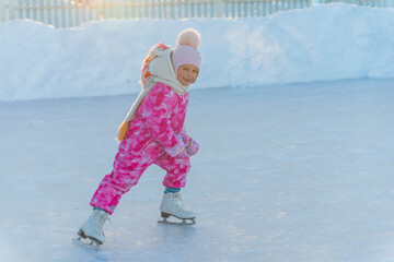 girl in pink overalls and pink hat skating on street rink
