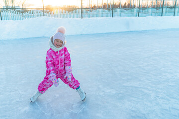 girl in pink overalls and pink hat skating on street rink