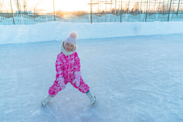 A little girl of 5 years old sits on a tubing and relaxes after skating on white figure skates at the skating rink in winter.