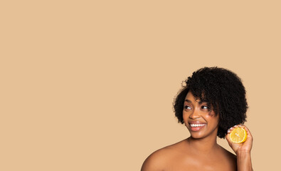 Joyful black woman with fresh lemon for skincare