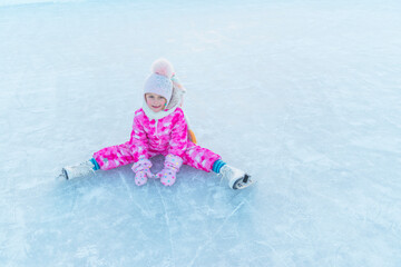 girl in pink overalls and pink hat skating on street rink