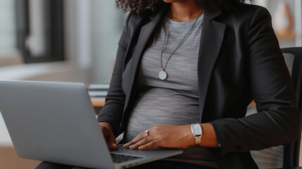 pregnant woman in a professional setting, working on a laptop.