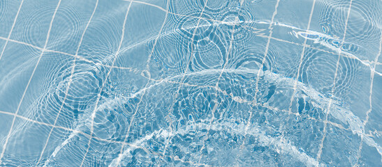 Clear water surface with ripple wave splashes and drops in swimming pool. Abstract turquoise or blue texture water wave and sunlight shadow reflections for background.