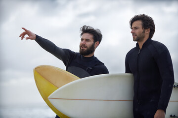 Man, friends and surfer pointing on beach for fitness, sport or waves on shore in outdoor exercise. Young male person or people with surfboard for surfing challenge or hobby on ocean coast in nature