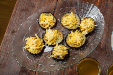 Eggplant with cheese and garlic on a transparent dish on the festive table