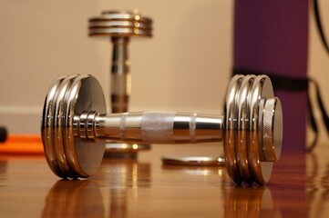 gym dumbbell on wooden floor. Gym chrome dumbbell on warm light.