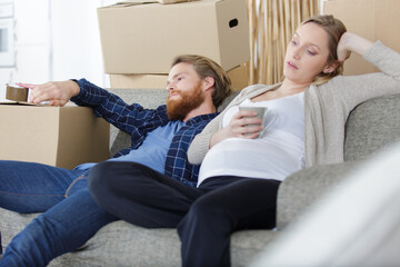 Fototapeta premium young pregnant couple sitting on sofa