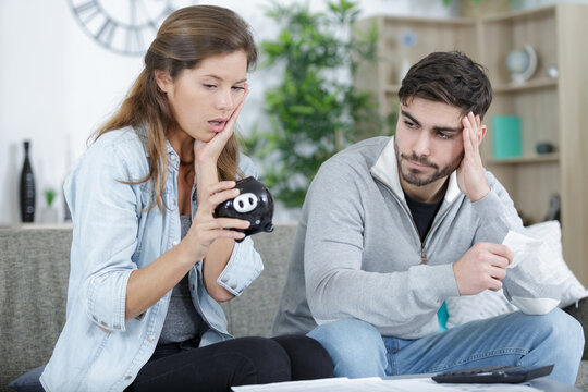 young broken down couple holding piggy bank