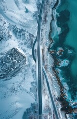an aerial view of a road next to a body of water in the middle of a snow - covered landscape.