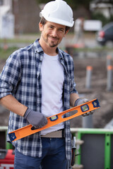 happy man checking level of wood at construction site