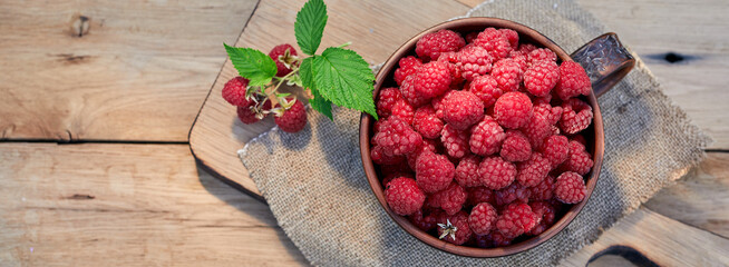 Sweet ripe raspberries in bowl on rustic wooden table. Close up summer photo in the garden. Top...