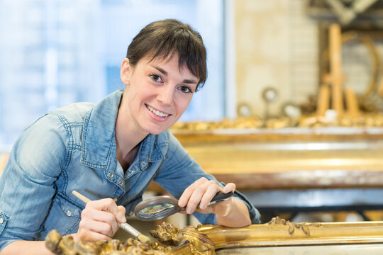 happy woman cleaning ancient frame gilder
