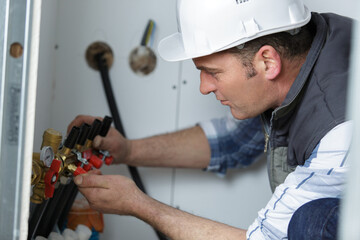 man openscloses hot water valve in the boiler-room
