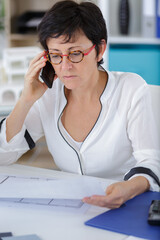 woman on the phone solving blue print issues