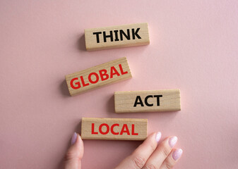 Think global act local symbol. Wooden blocks with words Think global act local. Beautiful pink...