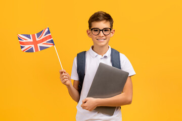 Study Abroad. Smiling Schoolboy In Eyeglasses Holding Laptop And British Flag