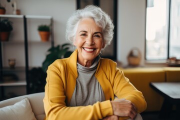 Fototapeta na wymiar Cheerful Senior Woman with White Hair in a Yellow Blazer Sitting Comfortably at Home