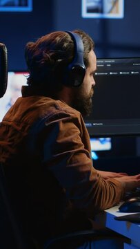 Engineer typing code in apartment office, using javascript programming language to develop software application. It admin using multimonitor desktop setup and notebook to finish tasks, camera A