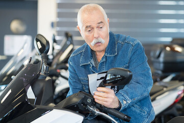 senior man choosing a motorcycle to buy