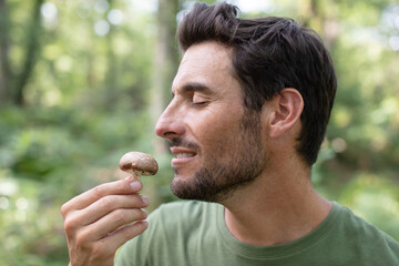 man in forest picking mushrooms smelling it