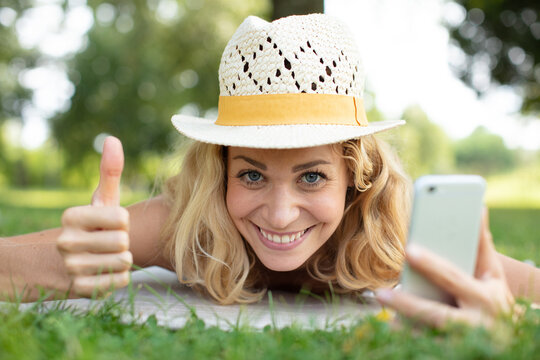 talking on mobile phone and thumbs up lying on grass