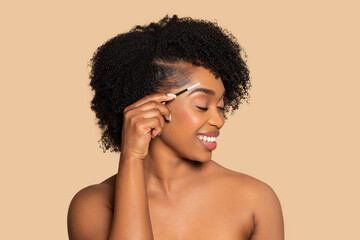 Happy african american woman grooming eyebrows with brush