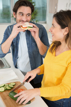 beautiful couple is eating sandwiches looking at each other