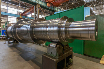 Shaft of big steam turbine in a factory workshop.