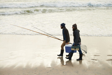 Calm, fishing and men walking on beach together with cooler, tackle box and holiday conversation. Ocean, fisherman and friends with rods, bait and tools at waves on winter morning vacation at sea.