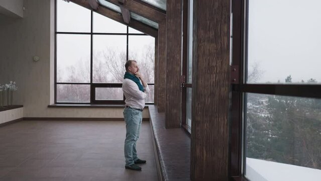 Man looks at winter landscape out of window