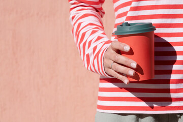 Woman in striped shirt holding red cup and drinking coffee