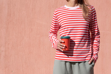 Woman in striped shirt holding red cup and drinking coffee