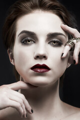 Beauty, woman and gothic makeup in studio with portrait for cosmetics, art deco aesthetic with edgy jewelry. Face of model in villain character, vampire and red lipstick on a dark or black background