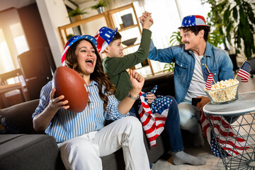 Latino family is watching rugby match with American flags.