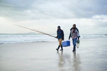 Winter, fishing and men walking on beach together with cooler, tackle box and holiday conversation. Ocean, fisherman or friends with rods, bait and tools in nature on morning vacation with cloudy sky - Powered by Adobe