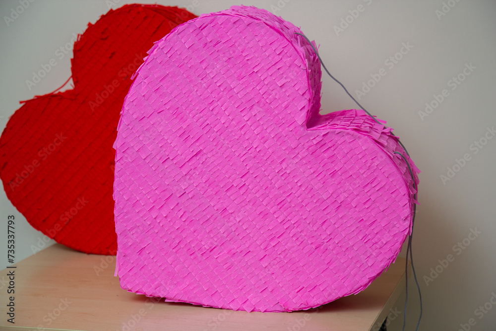 Wall mural red and pink heart on wooden table, heart shaped pinatas