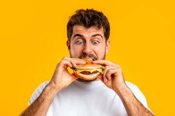 Caucasian man happily biting into a burger, portrait shot