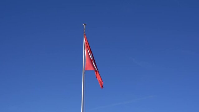 Swiss flag waving on top of Fronalpstock mountain in the Swiss Alps on a sunny winter day. Movie shot February 13th, 2024, Fronalpstock, Stoos, Canton Schwyz, Switzerland.