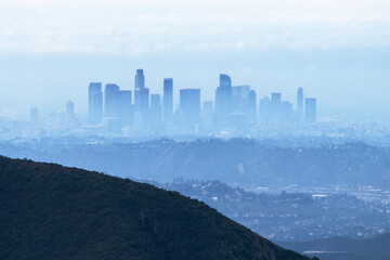 Fototapeta premium Storm haze and fog obscuring downtown Los Angeles skyline towers. Photo taken on Mt Josephine in the Angeles National Forest.