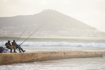Fishing, fisherman and people on pier by ocean with rod, reel and equipment to catch fish for hobby. Nature, sports and friends cast line for recreation or adventure on holiday, vacation and weekend