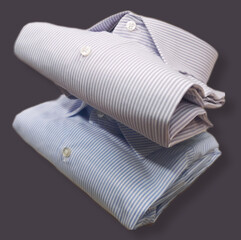 stack of two men's cotton shirts with english stick - purple striped shirt and light blue striped shirt isolated on dark background