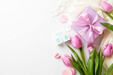 In bloom with affection: messages of springtime love on Women's Day. Top view of fresh tulips, cube calendar, gift box, tender hearts on white background with space for greetings or ads