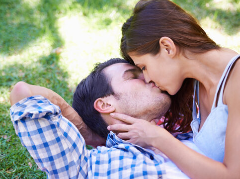 Couple, kiss and picnic on grass for love, bonding and connection on holiday in park outdoors. Relax, man and woman with romance for healthy relationship, commitment and date on vacation in Miami