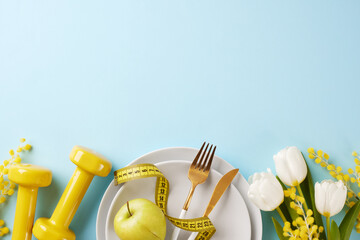 Spring shape-up: your guide to seasonal weight loss success. Top view shot of plates, cutlery, yellow dumbbells, measure tape, mimosa, tulips, apple on pastel blue background with promo slot