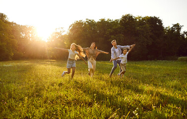 Happy family playing and having fun in nature. Cheerful, joyful mum, dad and children running...