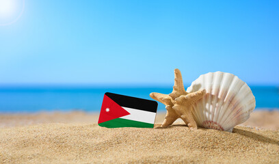Tropical beach with seashells and Jordan flag. The concept of a paradise vacation on the beaches of...