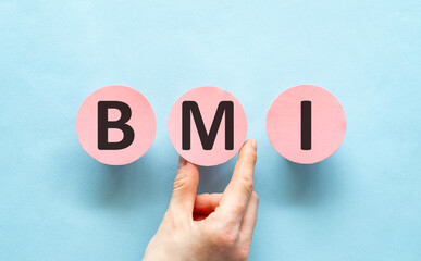 Pink circles with letters forming the acronym BMI held up by a hand against a blue background