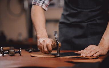 Artisan cobbler use hammer for working with leather textile for shoe at his workshop