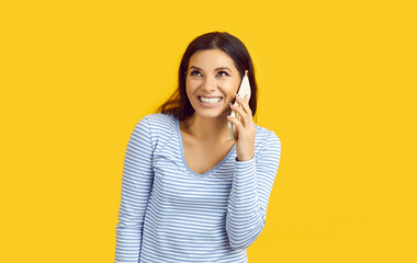 Studio shot of happy young woman calling someone on her mobile phone. Cheerful beautiful lady...
